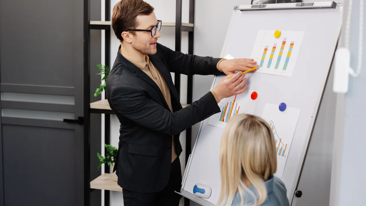Business consultant walking a client through charts on a flip chart