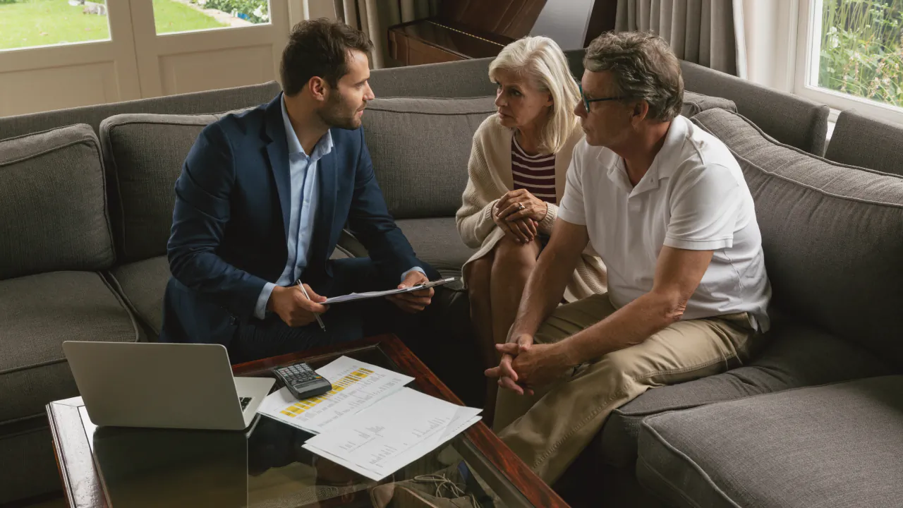 Financial adviser going through paperwork with a retired couple on their sofa at home