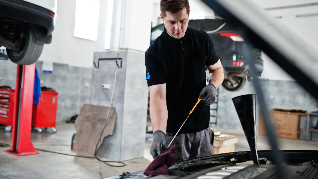 Mechanic checking the oil level of a car with its bonnet up in an independent garage