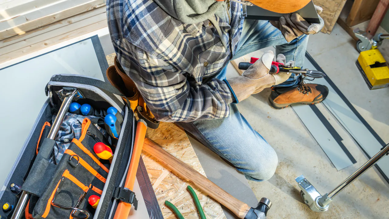 Maintenance contractor kneeling beside an open tool bag while working on a floor repair