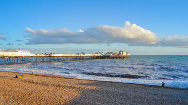 Brighton Palace Pier reaching out over the sea, seen from the shingle beach at sunset