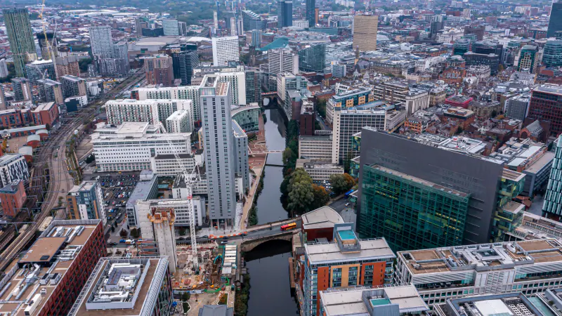 Aerial view of central Manchester on a sunny day, with the River Irwell running between the office buildings