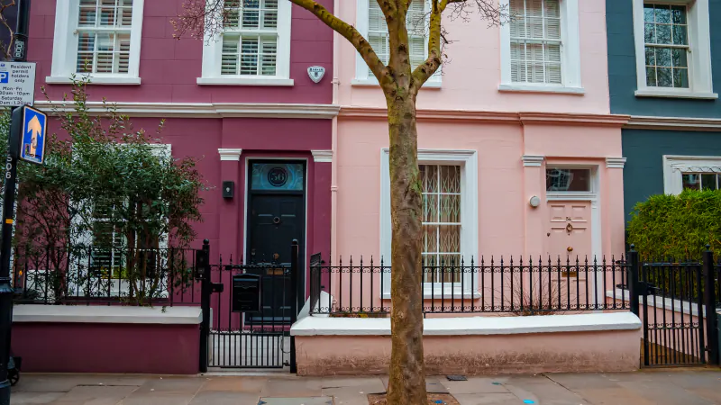 A terrace of pastel-painted houses on a tree-lined street in Notting Hill, West London