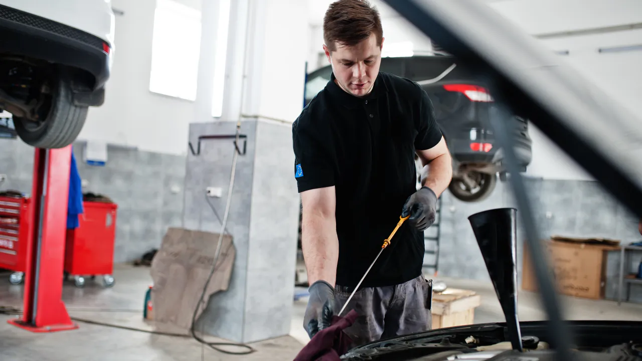 Mechanic checking the oil level of a car with its bonnet up in an independent garage
