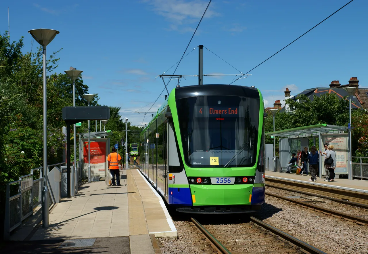 Tram arriving at Addiscombe tram stop with passengers waiting on the platform