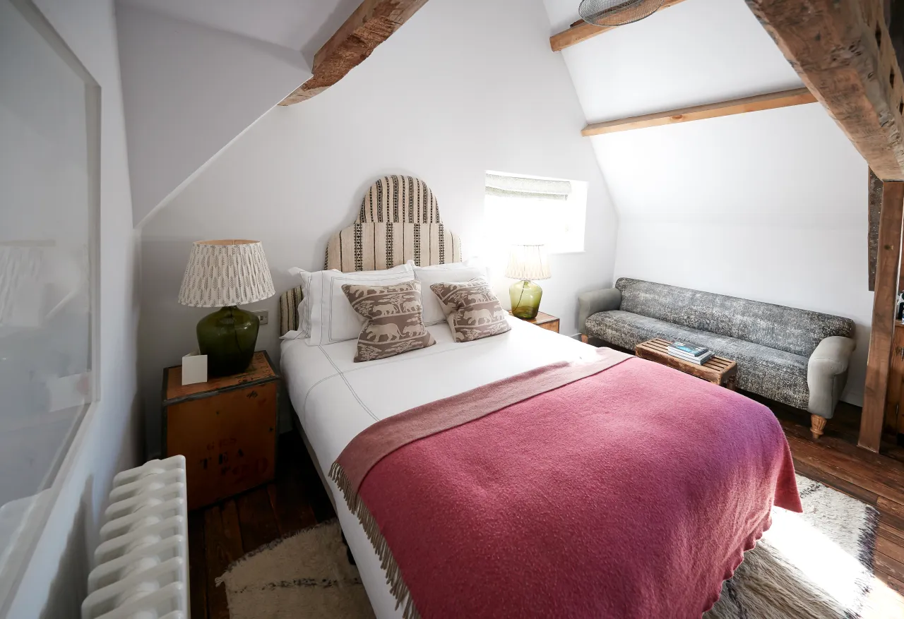 Cosy guest bedroom under the eaves in a bed and breakfast, with wooden headboard and warm throw