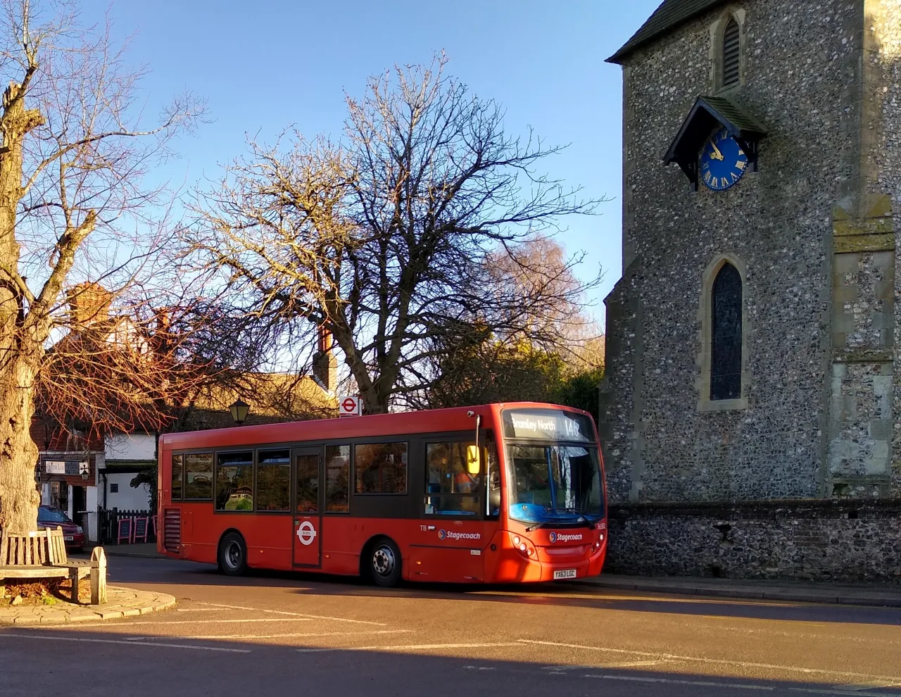 A red London bus beside St Mary's Church in Downe, a village in the rural south of the London Borough of Bromley