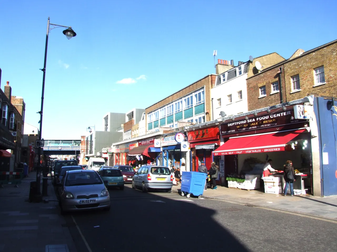 Deptford High Street with shops, market stalls and the railway bridge, SE8