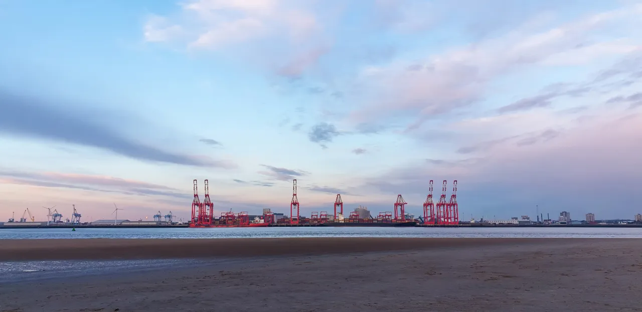 View of Liverpool's port at dusk, cranes loading cargo onto ships, showing UK port capability
