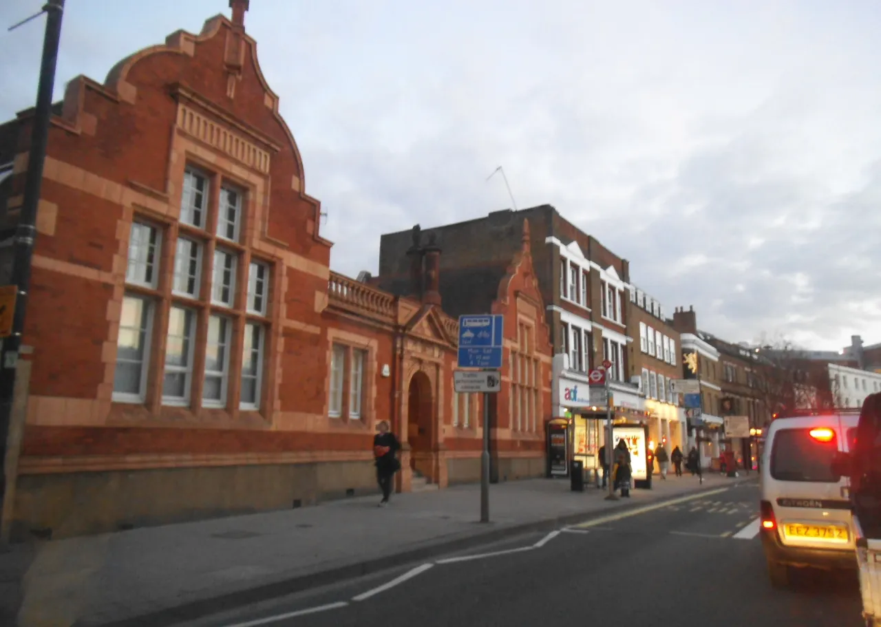 Buildings and shops along Fulham High Street, London, with pedestrians and a bus