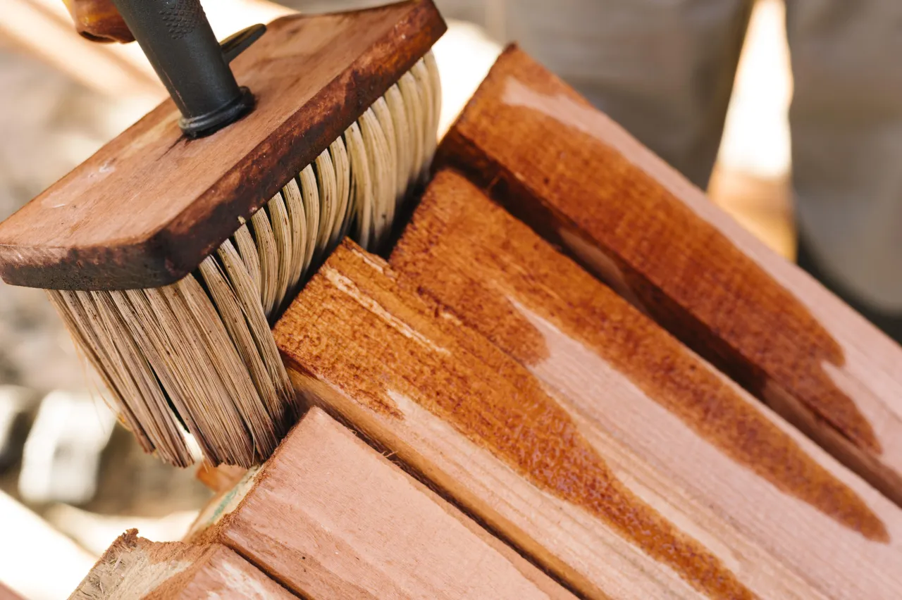 Close-up of a brush applying varnish to a wooden furniture piece
