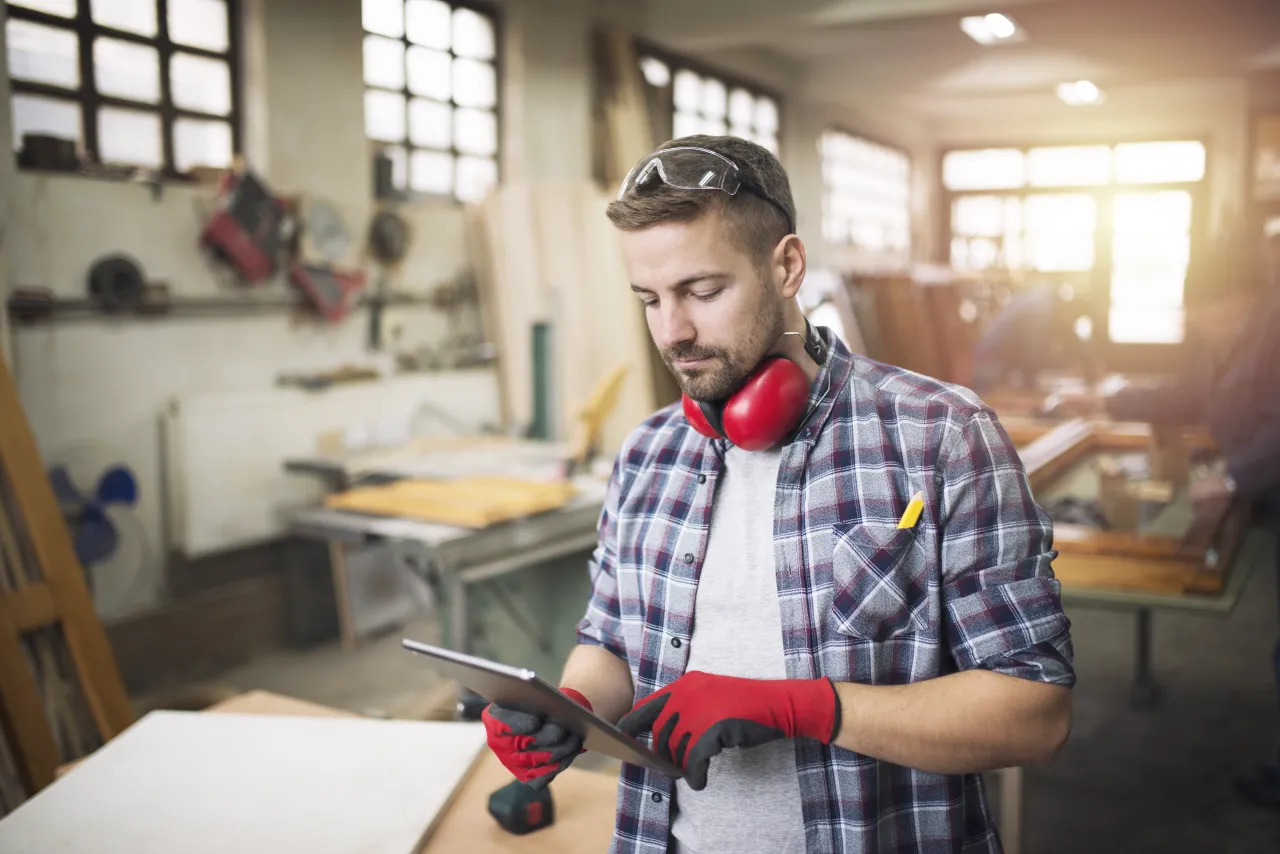 Carpenter checking a tablet while working on a restoration project in his workshop