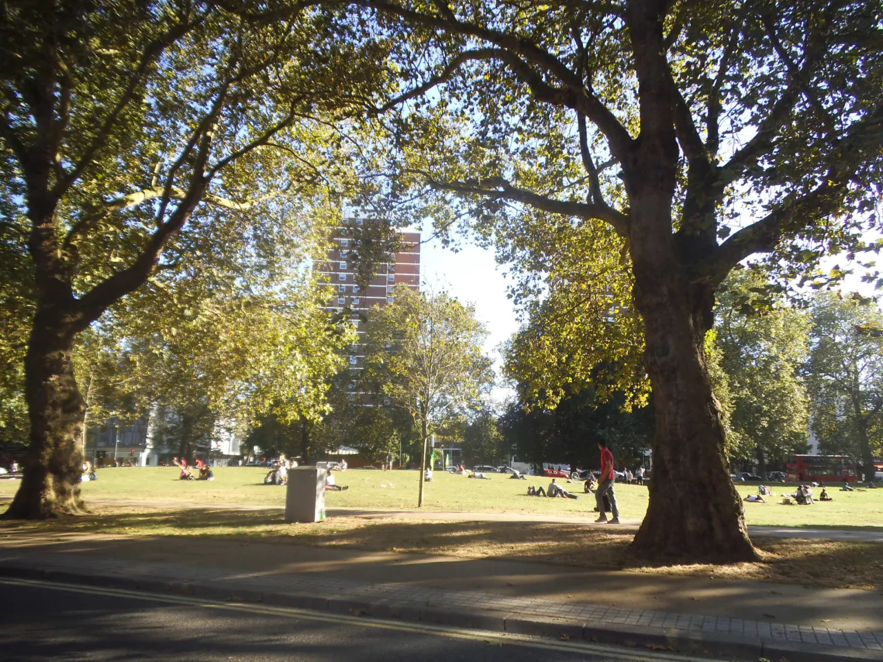 Shepherd's Bush Green with trees and people relaxing on the grass