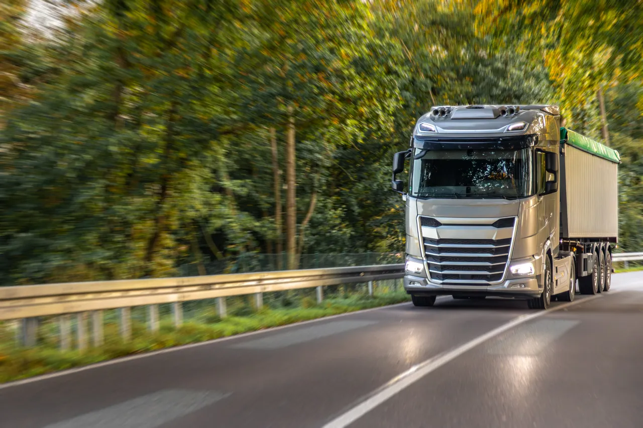 European lorry travelling a winding forest road mid-journey, freight in transit