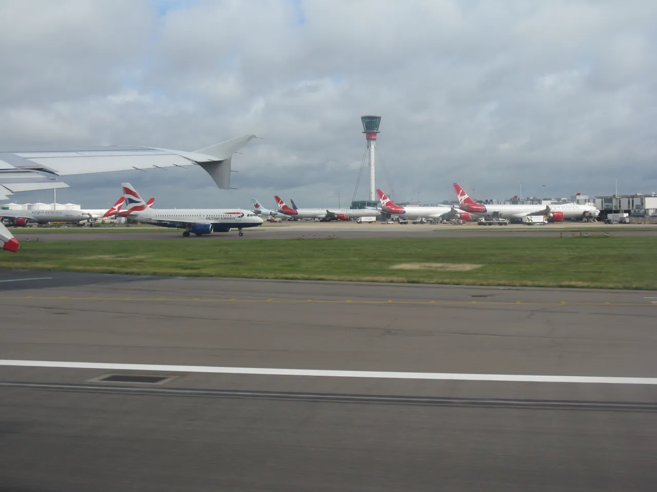 Aircraft on the taxiway at Heathrow Airport with the air traffic control tower in the background