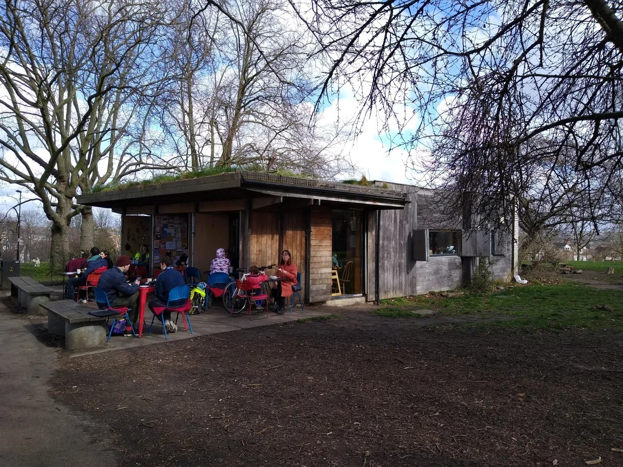 Hilly Fields park in Lewisham, with the park cafe shelter and people sitting outside