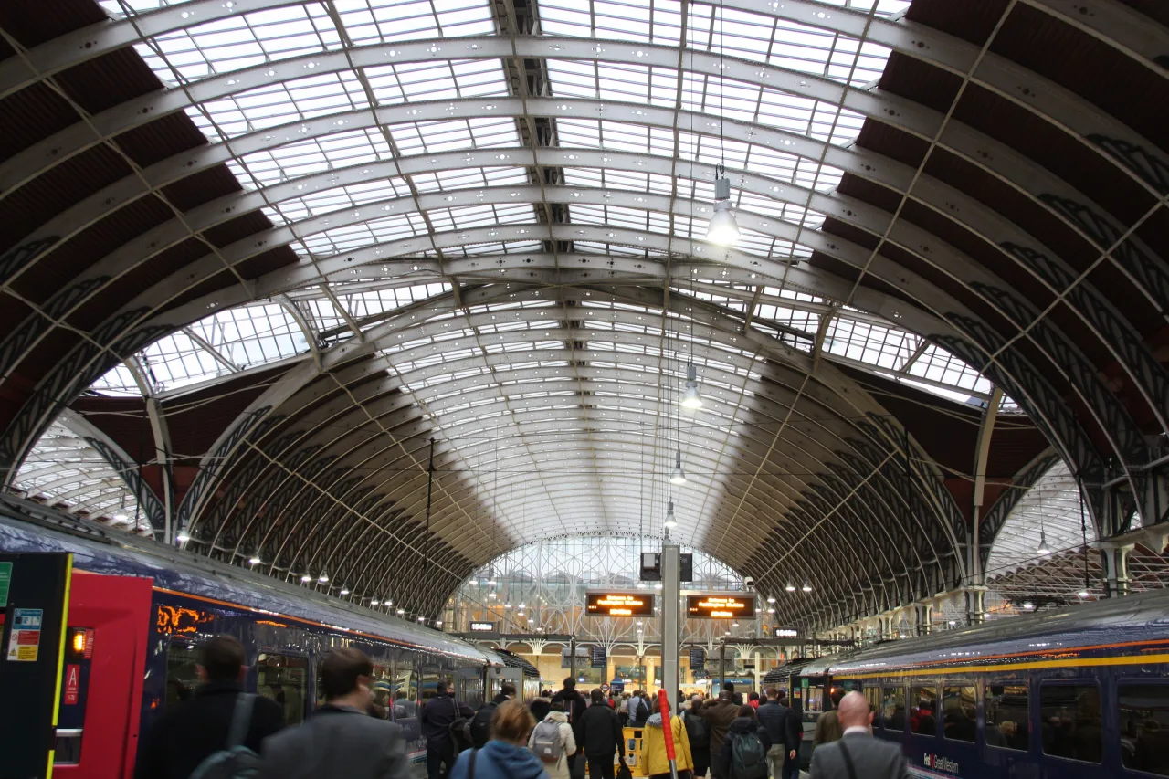 Commuters walking through Paddington station's Brunel train shed beneath the arched glass roof