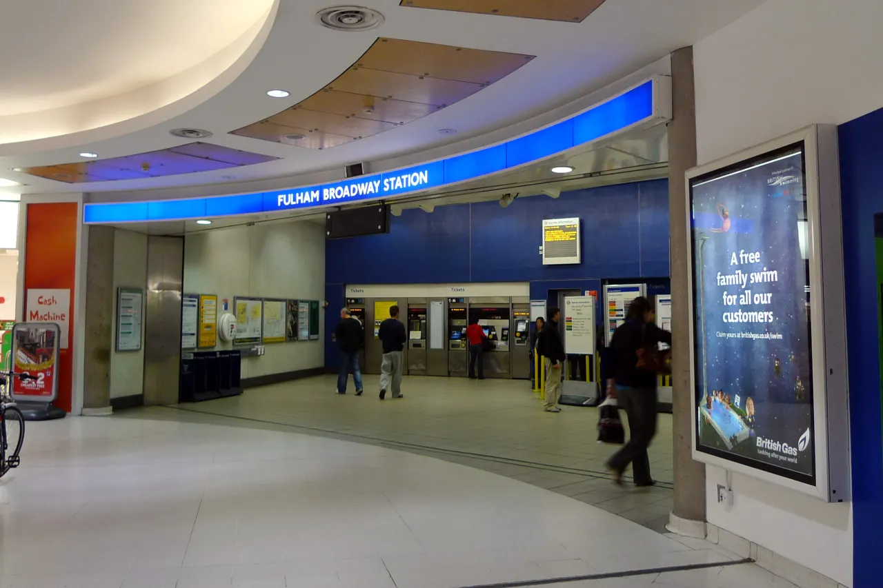 Interior of Fulham Broadway station, with the shopping centre entrance and passengers