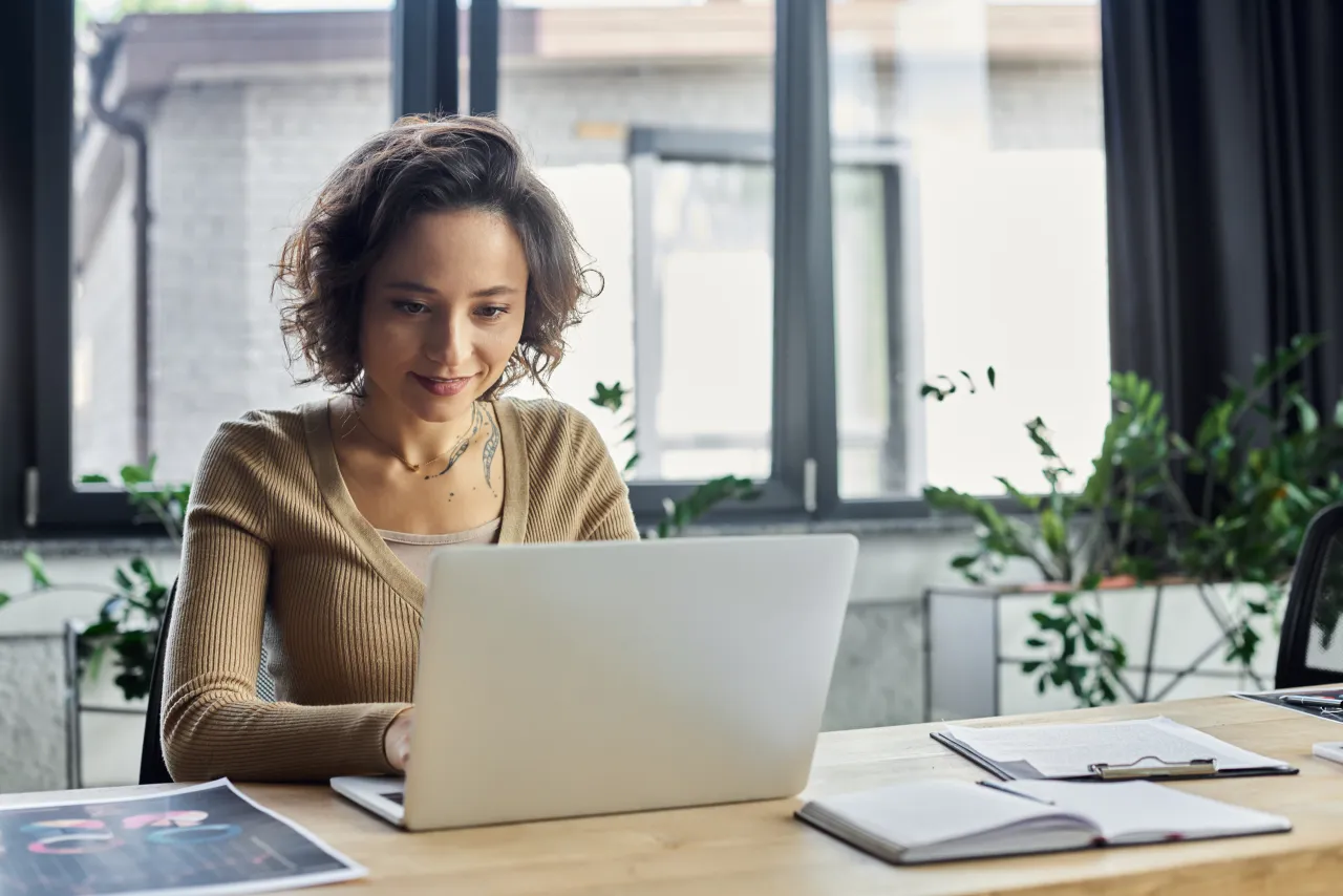Consultant working at a laptop with case notes, natural light, calm working environment
