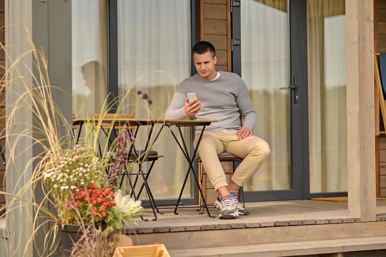 Homeowner sitting outside their house checking a planning question on their phone
