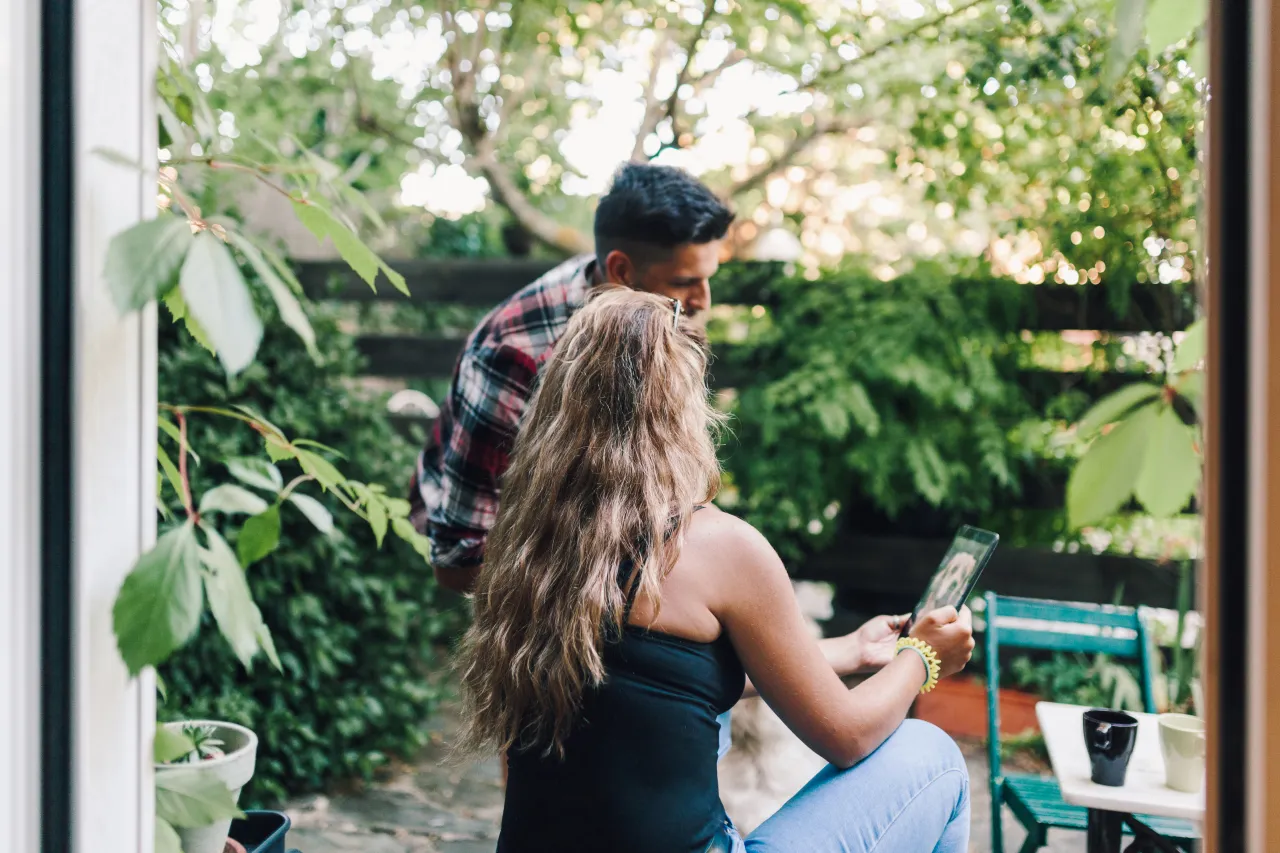 A couple in their back garden checking details on a tablet together before committing to a pool project