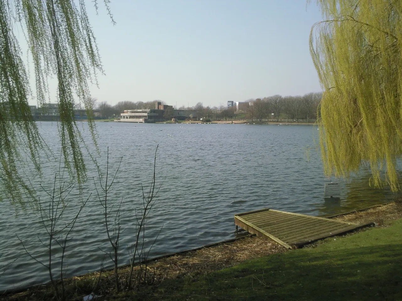 Southmere Lake, Thamesmead, viewed through willow trees towards the lakeside pavilion