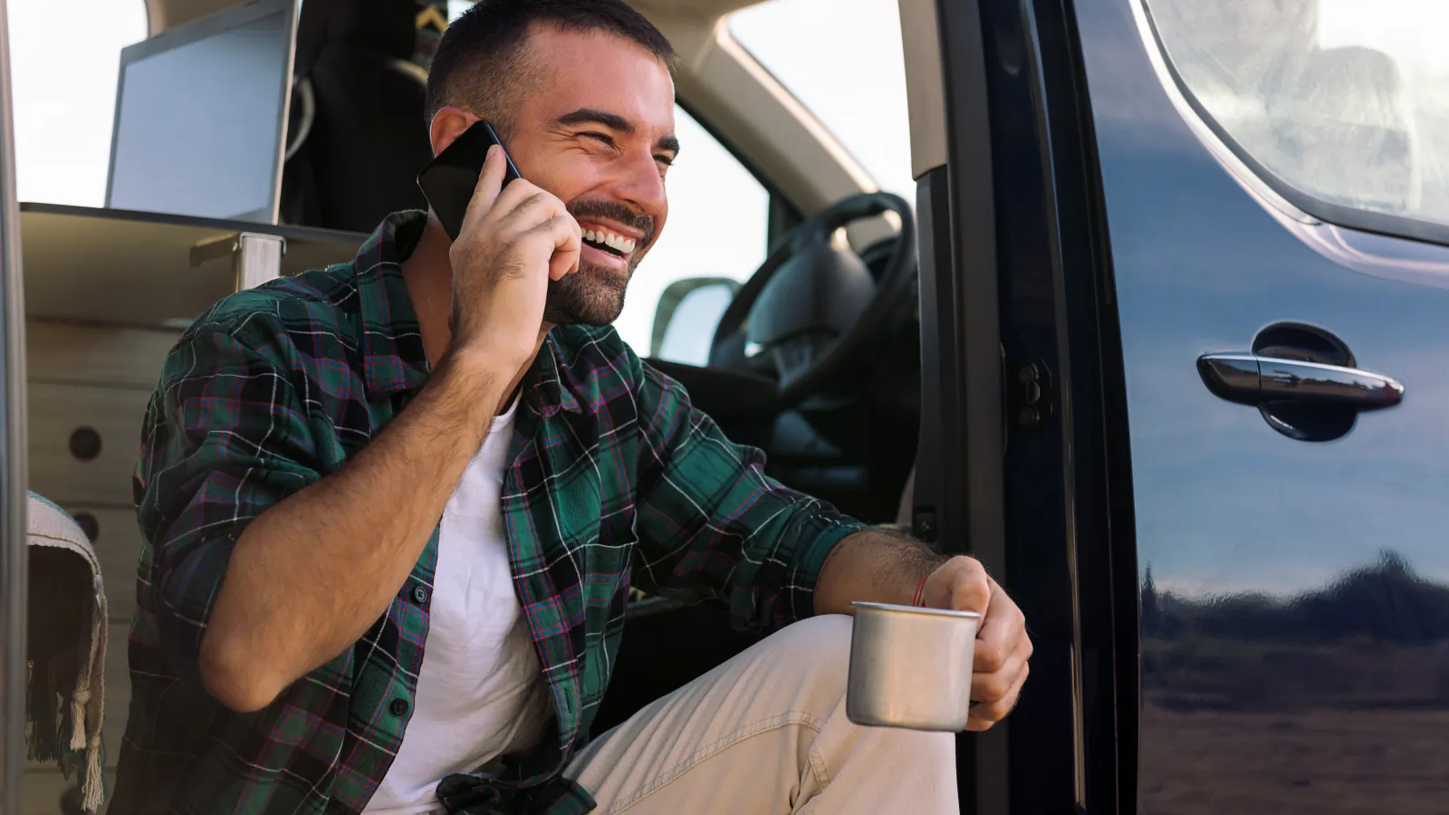 A tradesman taking a call while sitting in the doorway of his van